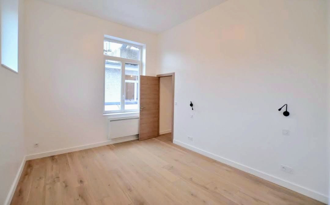 Chambre rénovée avec parquet chêne, applique noire et porte en bois