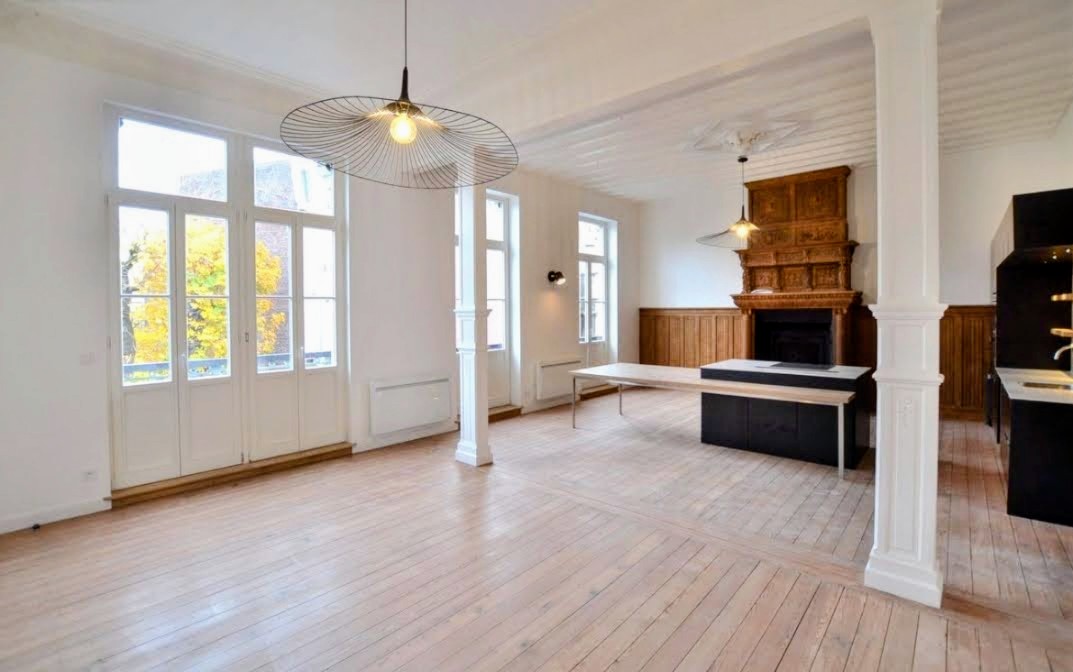 Grand séjour à parquet ancien avec colonnes, moulures et cheminée en bois sculpté
