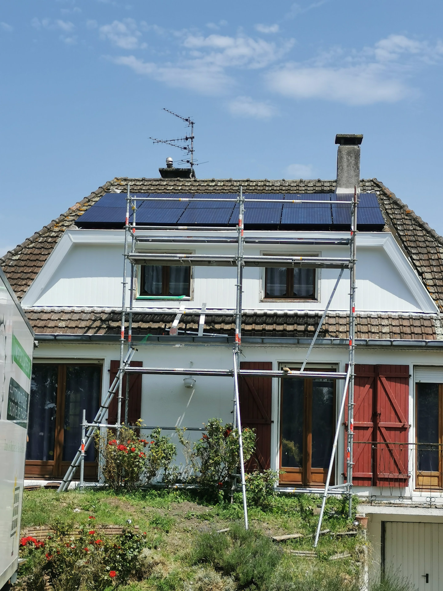 Panneaux photovoltaïques posés sur une toiture ancienne en tuiles, échafaudage complet devant la façade