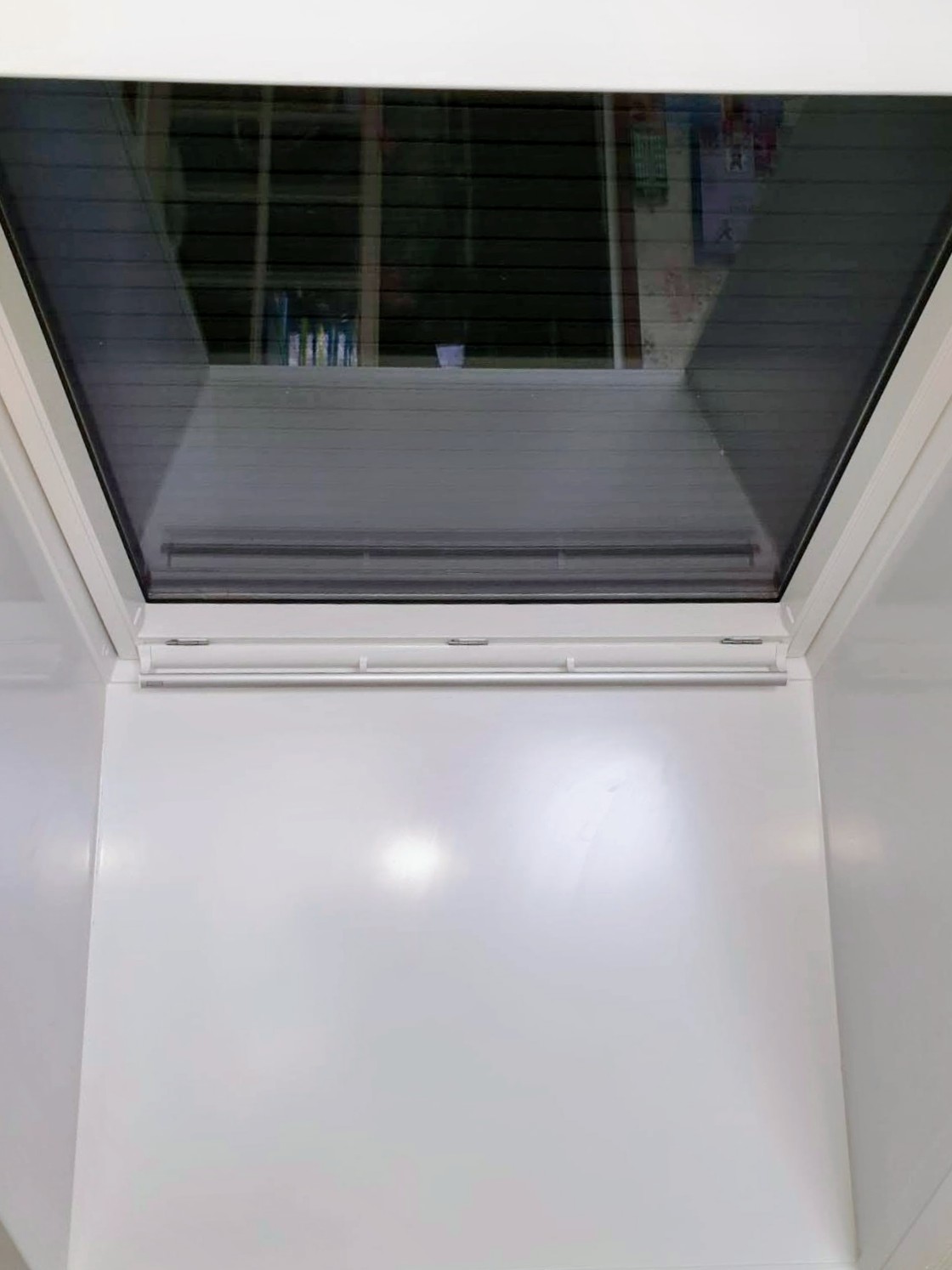 Détail intérieur d'une fenêtre de toit blanche équipée d'une moustiquaire enroulable et d'un store occultant replié