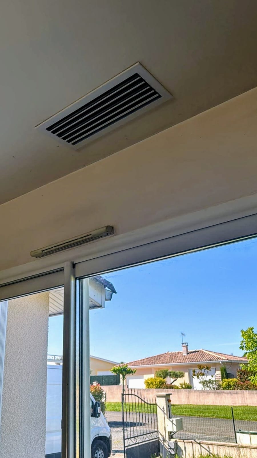 Bouche de soufflage rectangulaire encastrée au plafond au-dessus d'une baie coulissante, entrée d'air en imposte