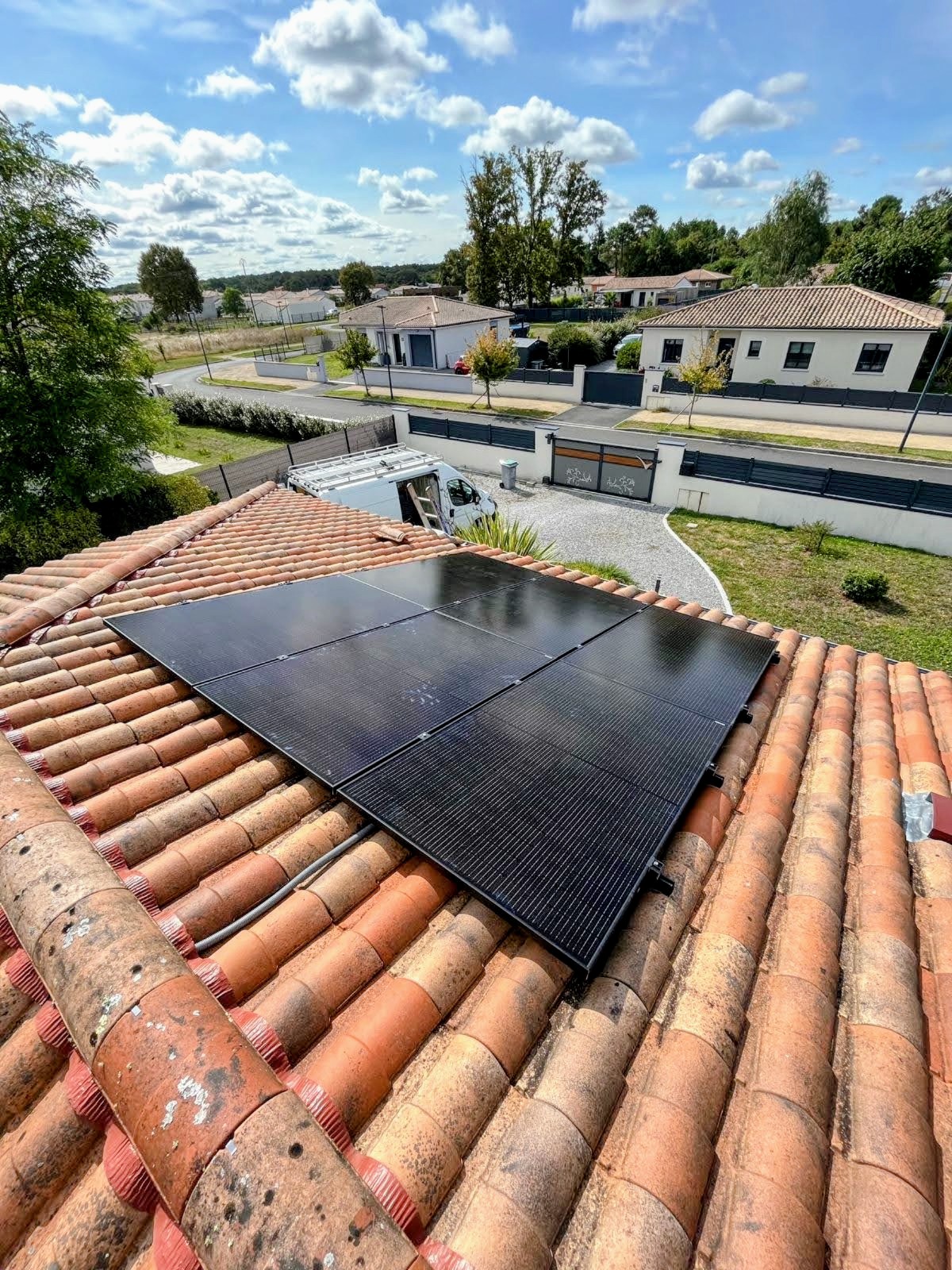 Champ de six panneaux photovoltaïques noirs sur une toiture en tuiles dans un lotissement