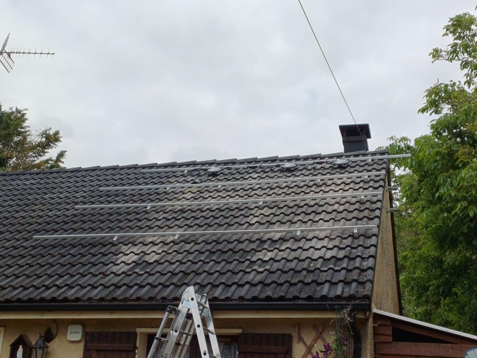 Rails de fixation photovoltaïques posés sur une toiture en tuiles mécaniques sombres, avant la mise en place des panneaux