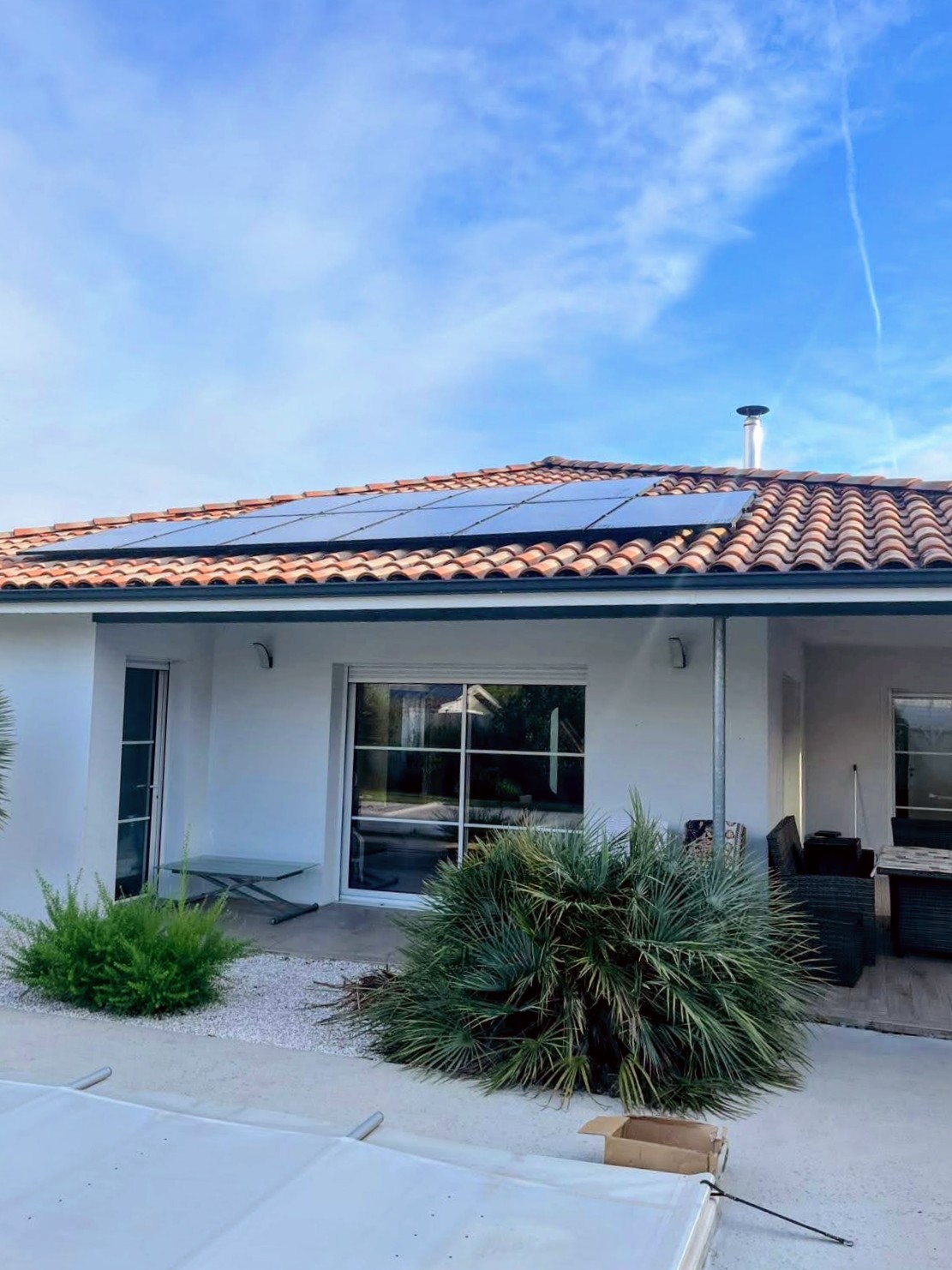 Maison contemporaine de plain-pied à enduit blanc et tuiles canal, équipée de panneaux photovoltaïques, terrasse et piscine au premier plan