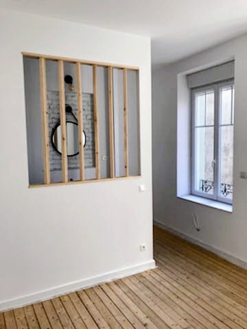Verrière à ossature bois en cours de montage contre un mur de brique intérieur, vitrages posés partiellement