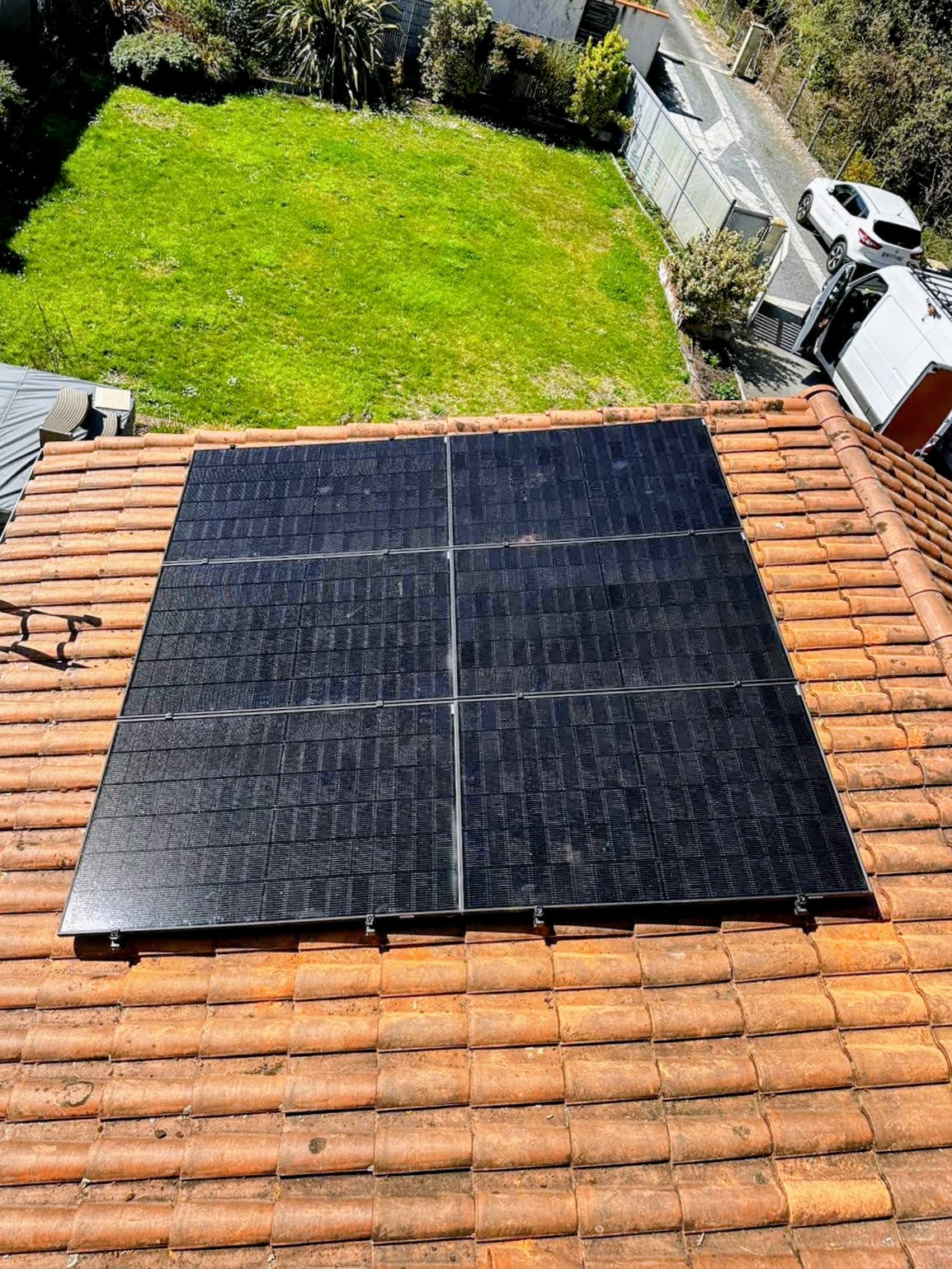 Champ de panneaux photovoltaïques noirs posé sur une toiture en tuiles, vue en hauteur