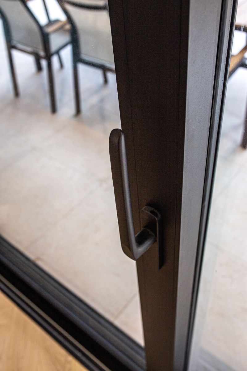 Détail d'une poignée de menuiserie aluminium noire sur un ouvrant